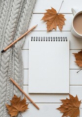 Cozy autumn workspace flat lay featuring a notebook pencils a warm drink and textured fabric for creative inspiration and seasonal comfort