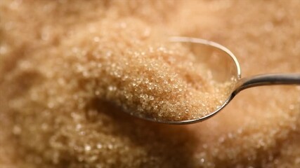 Brown Cane sugar in a spoon close up. Brown sugar background. Heathy eating, diet concept. Top view, flat lay, slow motion, rotating  - Powered by Adobe