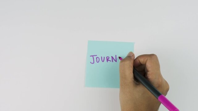 hand with marker writing 'Journal Daily' on sticky post it note isolated on white background, journaling, self affirmations and positive habits concept stock footage 