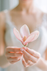 Naklejka premium Delicate magnolia flower gently held in manicured hands