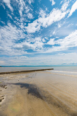 Sunny beach with pier stretching into the calm blue Gulf of Trieste near Grado, Italy