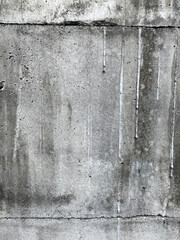 A close-up of a darker concrete wall featuring visible vertical streaks caused by water or weather exposure.