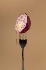 Sliced purple onion on a fork with dripping honey. Abstract modern style