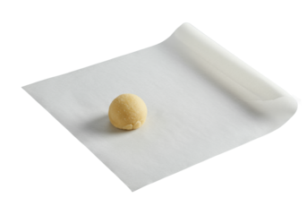transparent baking parchment paper with folded corner, and unbaked light beige sugar cookie dough ball on seamless gray background, studio lit, concept of kitchen utility