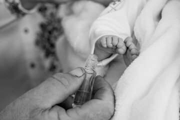 Black and White Baby Christening Foot Anointing with Oil, Close-up Ritual, Newborn Faith, Church Ceremony, Soft Focus Texture