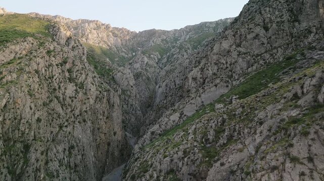 Aerial view into a dramatic cliff corridor in the Uzbekistan mountain region. Sheer rock and shadow form powerful contrast, the space feels remote, pristine, and ready for tourism content