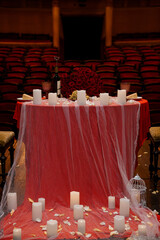 Romantic Valentine's Day Table Setting in Theater: Red Roses, Wine, Candles, Dramatic Lighting, Intimate Event.