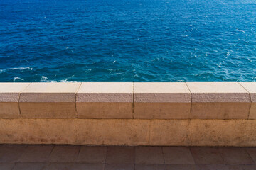 Classic stone balustrade on the Promenade des Anglais overlooking the vibrant blue Mediterranean Sea in Nice, French Riviera.