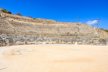 A large empty amphitheater with a blue sky above. Ruins of the ancient city of Philippi, Greece