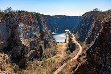 Stunning limestone quarry with serene blue lake and rocky cliffs under clear sky