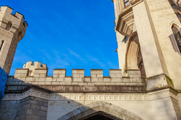 Medieval stone castle walls and arched entry against clear blue sky