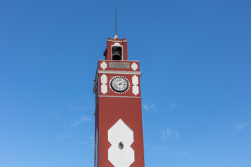 Marchena, Andalusia, Spain. 4 September 2025. Red and white clock tower with bell and Roman numerals