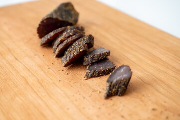 Piece of Beef Biltong Cut Into Pieces on Maple Cutting Board 