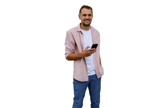 Young man smiling while holding mobile phone, connecting with technology, using app, standing on transparent background