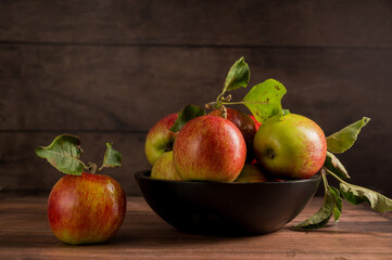 Freshly picked red apples in a bowl, rustic wooden background