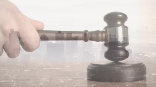 Pale hand swinging wooden gavel onto block executing strike then lifting it above skyline