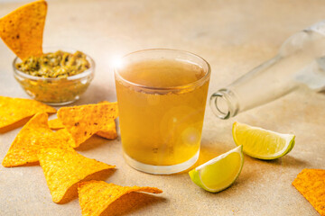 Cold beer with tortilla chips, dip and lime on stone table