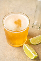 Glass of cold beer with heart shaped foam and lime on stone table
