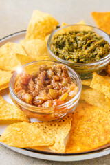 Tortilla chips with spicy vegetable dips in glass bowls