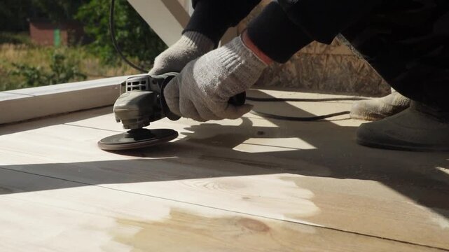 Skilled worker sanding wooden surface for smooth finish on outdoor decking project