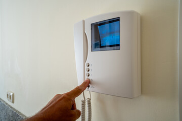 Finger pressing button on home video intercom security system with screen display