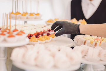 Delightful sweet treats displayed at a festive event with a dedicated server carefully arranging desserts at a dessert table