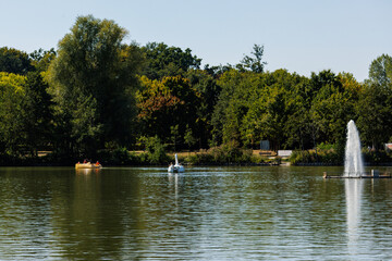 Pedal boats and fountain in natural lake surrounded by trees
