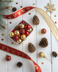 Flatlay with baubles, pinecones and ribbon on white wooden texture, cozy winter holiday mood