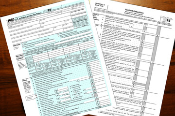A 2025 IRS 1040 tax form and a schedule A itemized deductions form lay on a table