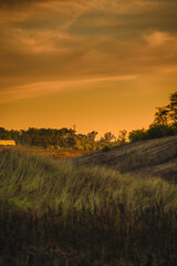 Fototapeta premium A long, blurry shot of a train in the distance, passing by hills in the golden autumn twilight.