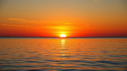 Fototapeta premium Beautiful sunset over calm ocean water, warm glowing horizon with orange and red tones.