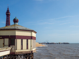 old building on Blackpool North pier with Blackpool tower and the Central pier in the distance in summer sunshine