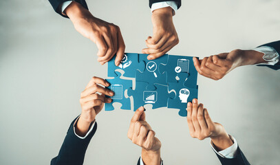 Hands of diverse professionals collaboratively assembling puzzle pieces, symbolizing teamwork and...