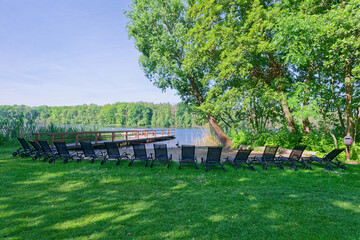 Lakeside lawn with wooden pier duck and rows of black loungers