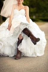 Happy Bride in Wedding Dress and Brown Cowboys Boots Sitting Outside