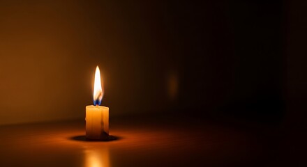 A solitary candle burns brightly, casting a warm, orange glow against a dark, somber background.
