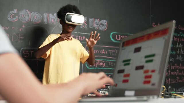 Closeup of school girl hand coding program while african student using VR interact with metaworld. Smart boy wearing virtual reality glasses and playing video games at innovative class. Edification