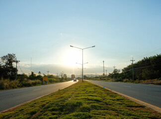 Evening wind powers turbines over a summer highway, connecting the city to the green rural landscape