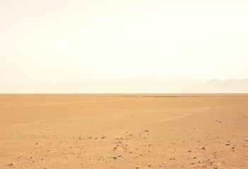 Vast desert landscape with sandy dunes under a hazy sky