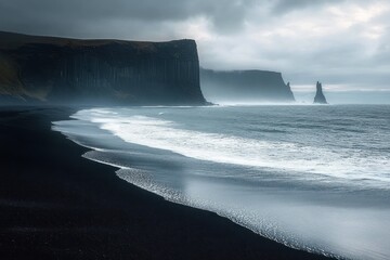 Moody seascape with black sand beach, basalt cliffs, and sea stacks under a cloudy sky creating a dramatic and serene atmosphere