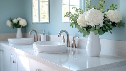 Bright modern bathroom countertop with white vessel sinks, silver faucets, and elegant white vase filled with lush white flowers and green foliage, soft natural light
