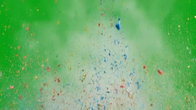 A chaotic and scattered explosion of multi-colored powder particles erupting randomly against a green screen disorderly, graphic, unpredictable