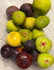 Variety of colorful figs inside plastic container.