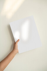 Hand holding a sheet of paper against the green wall