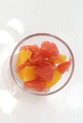 Fresh peeled pomelo fruit, grapefruit, orange. Citrus fruits. Bowl on white table. Ready to eat citrus dessert, healthy eating