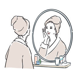 鏡の前に立つバスローブ姿の女性