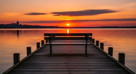 Wooden pier with bench at sunset over calm lake water.