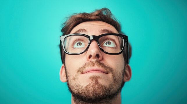A man with glasses looking up against a blue background. The man's facial expression is one of surprise or confusion.