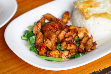 Delicious Culinary Delight: A top-down shot of a plate with rice, topped with fried egg and a mix of stir-fried pork belly and greens, evoking sensations of culinary bliss.
