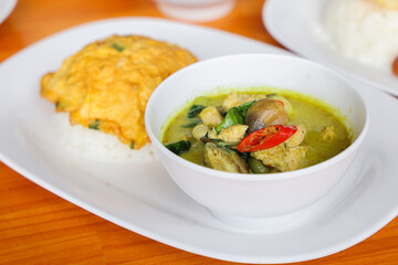 Thai Green Curry with Rice: Aromatic Thai green curry served in a pristine bowl, paired with fluffy white rice and a vibrant omelet.